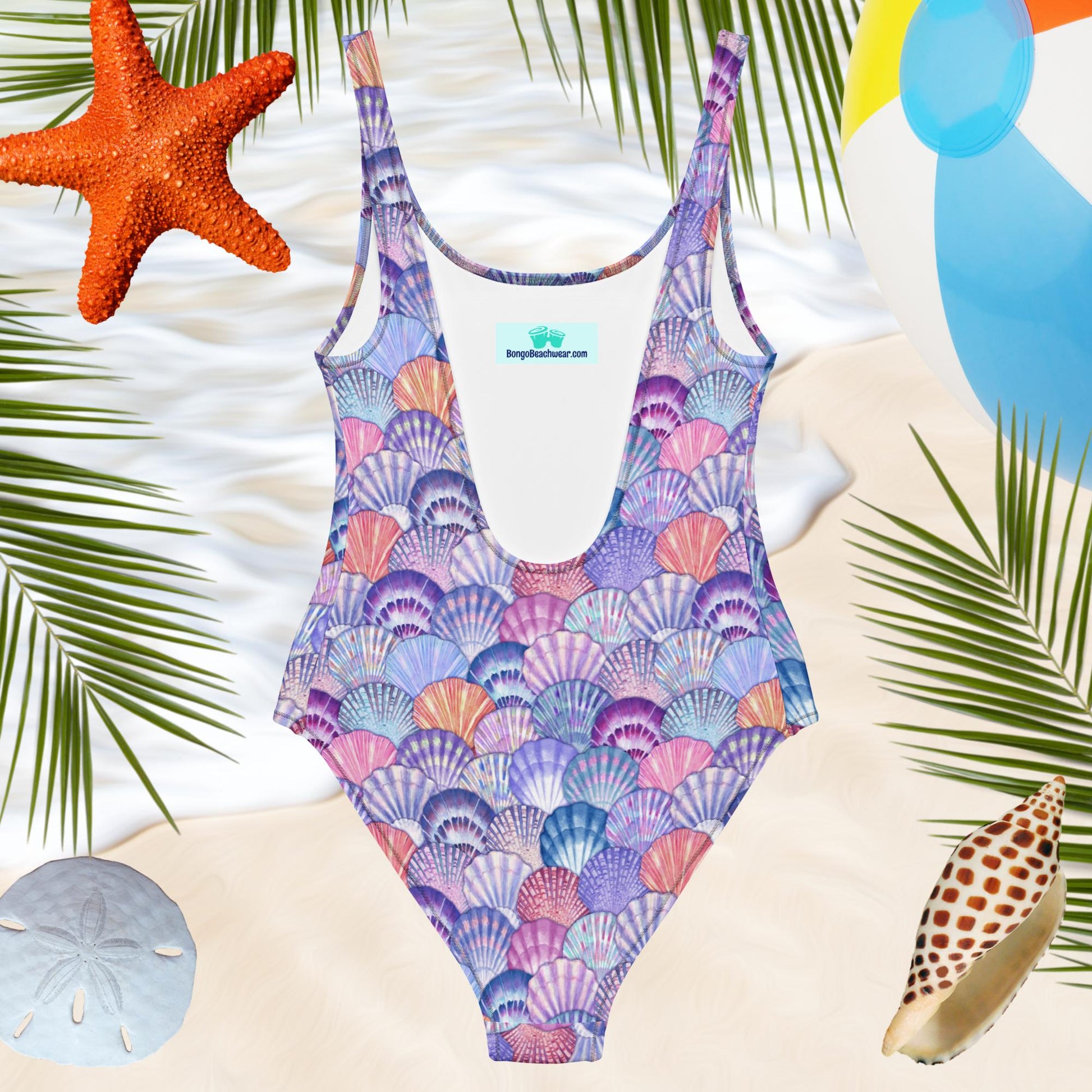 Back of Ladies one piece Seashell Pattern swimsuit over a beachy background