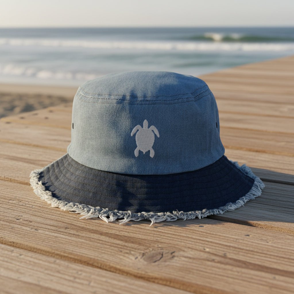 Blue bucket hat with white seaturtle embroidery on a beachside boardwalk