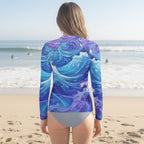 Teen girl wearing a long-sleeve swimsuit with a blue and purple wave pattern on a La Jolla Beach