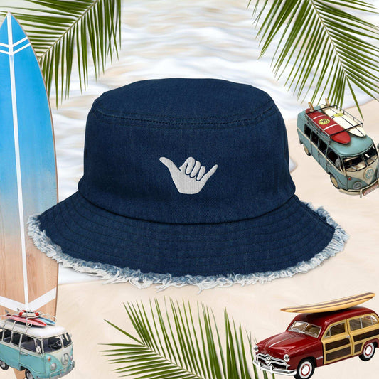 Shaka Blue Jean Bucket Hat with Hang Loose logo, perfect for surfers and stylish beachgoers, set against a tropical backdrop.
