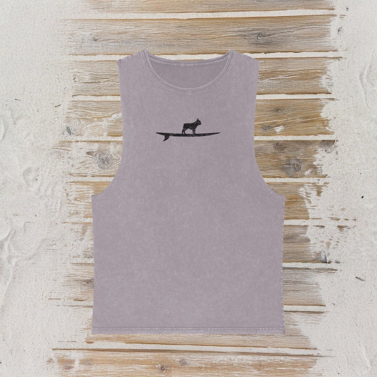 A sleeveless light purple tank top featuring a black silhouette of a french bulldog standing on a surfboard on the chest, displayed flat against a rustic wooden plank background.