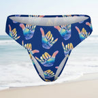 Blue bikini bottom with colorful hang loose shaka sign on a faded beach scene background