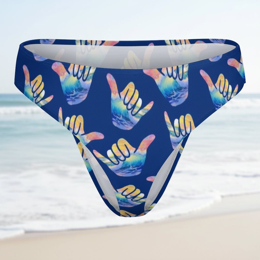 Blue bikini bottom with colorful hang loose shaka sign on a faded beach scene background