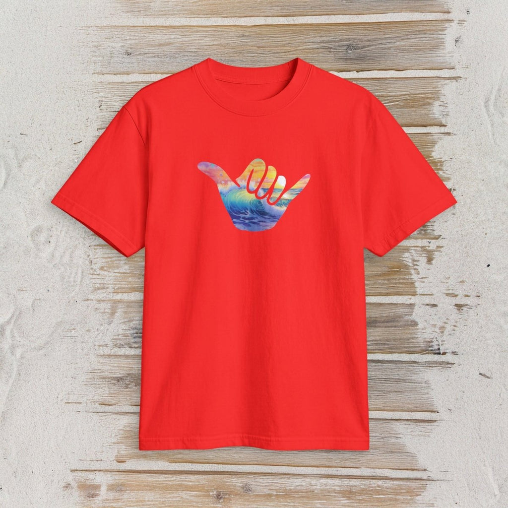 A bright red short-sleeve t-shirt with a colorful graphic of a hand making a shaka sign over a sunset and ocean scene, displayed flat on a rustic light wood background.