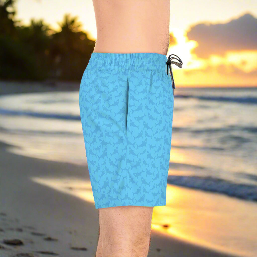 guy wearing blue shark pattern bathing suit standing on the beach