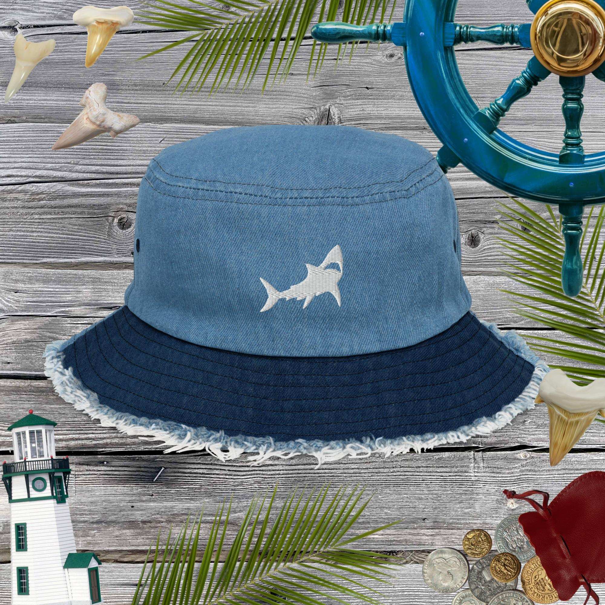 Blue bucket hat with shark design on a wooden surface with nautical decorations.