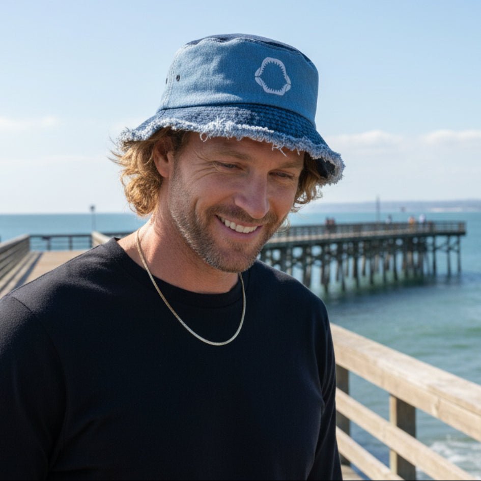 Man wearing a blue bucket hat with embroidered shark jaws, fishing for sharks from Gulf Coast Pier