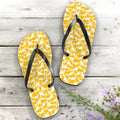 Pair of yellow shark flip-flops with black straps on a wooden surface.