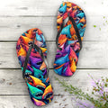 Colorful shark-patterned flip-flops on a wooden surface with flowers.