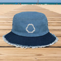 A two-tone blue bucket hat made of washed light blue denim on the crown and a darker navy blue denim brim with frayed edges. A white embroidered shark-tooth motif is stitched on the front center of the crown.