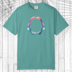 A green short-sleeve t-shirt with a colorful graphic of a shark mouth on the chest, displayed flat against a white wood plank background.