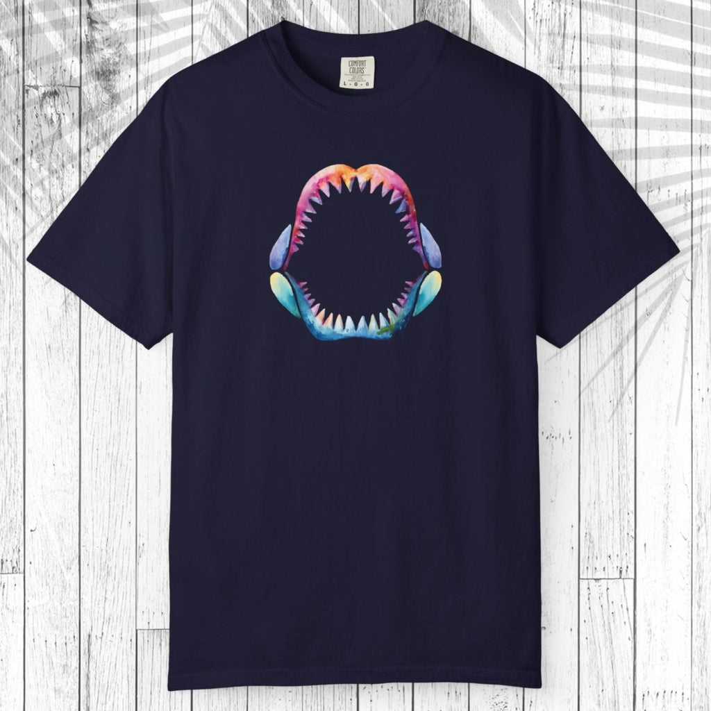 A navy blue short-sleeve t-shirt with a colorful graphic of an open shark mouth on the chest, displayed flat against a white wood plank background.