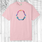 A light pink short-sleeve crewneck t-shirt featuring a colorful graphic of an open shark mouth with sharp teeth on the chest, displayed flat against a white wood plank background.