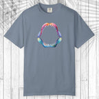 A teal short-sleeve t-shirt with a colorful graphic of a shark mouth on the chest, displayed flat against a white wood plank background.