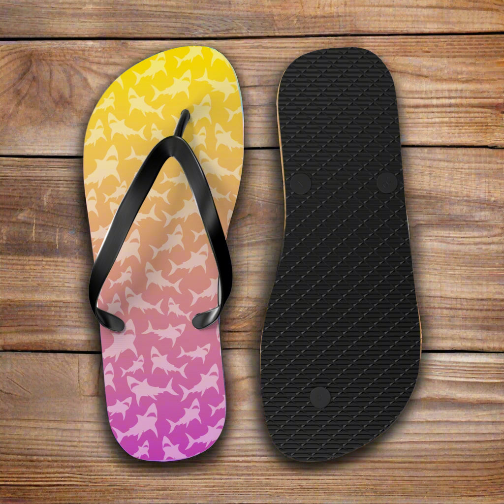 Flip-flop with colorful shark pattern and black insole on a rustic nautical wood background