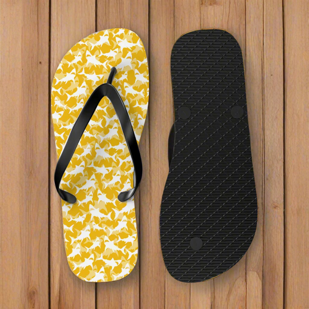 Flip-flop with yellow shark pattern and black strap on the deck of a vintage sailboat moored to a pier in the virgin islands