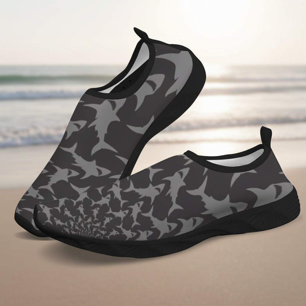 A pair of slip-on water shoes with a dark gray and black shark pattern, shown on a faded man wearing these shoes getting ready to do a little surf fishing on new smyrna beach background.