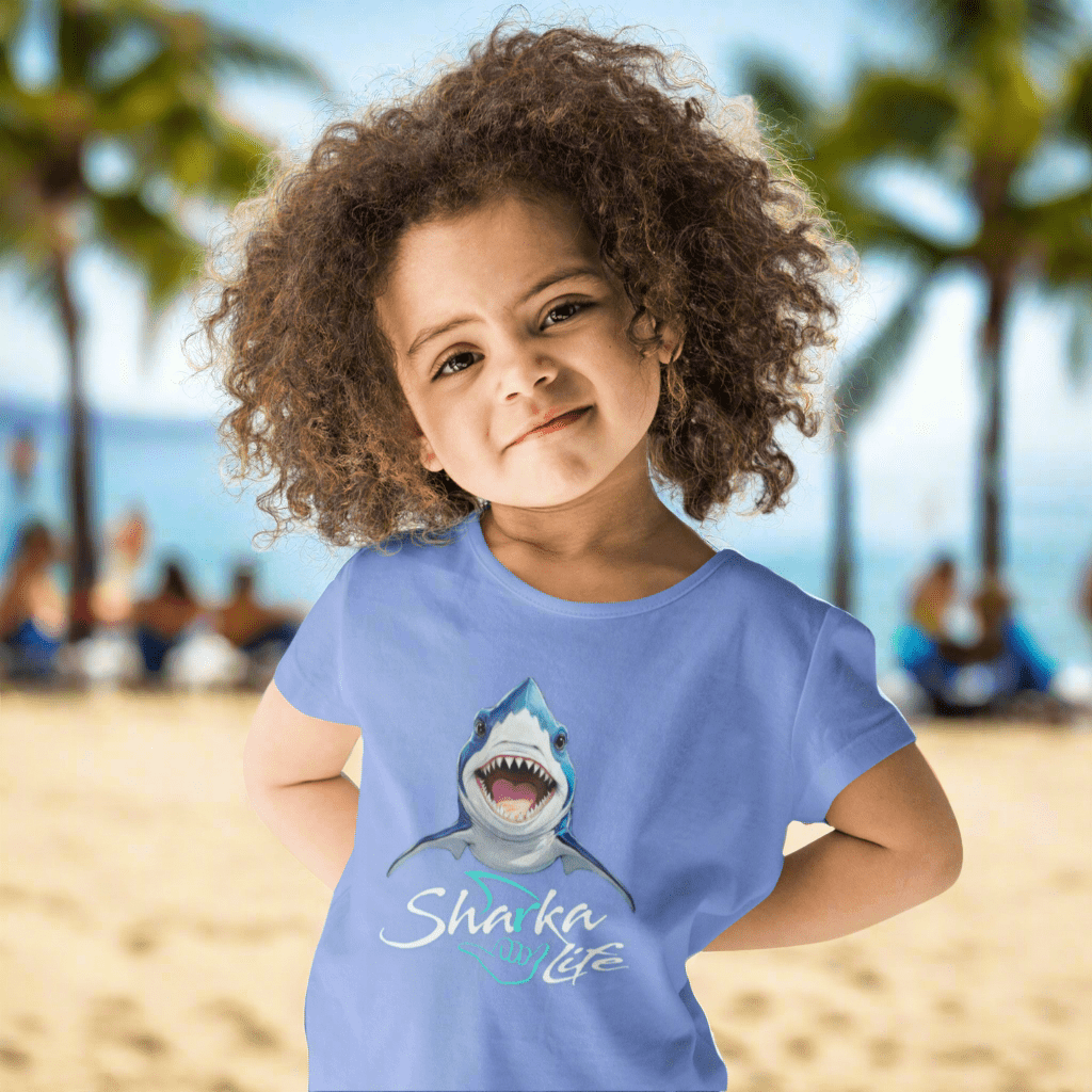 Child wearing a blue t-shirt with a shark graphic and the text; Sharka' Life. just hanging out in Waikiki