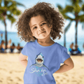 Child wearing a blue t-shirt with a shark graphic and the text; Sharka' Life. just hanging out in Waikiki