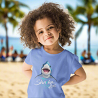 Child wearing a blue t-shirt with a shark graphic and the text; Sharka' Life. just hanging out in Waikiki
