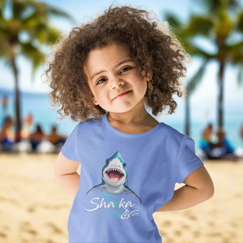 Child wearing a blue t-shirt with a shark graphic and the text; Sharka' Life. just hanging out in Waikiki