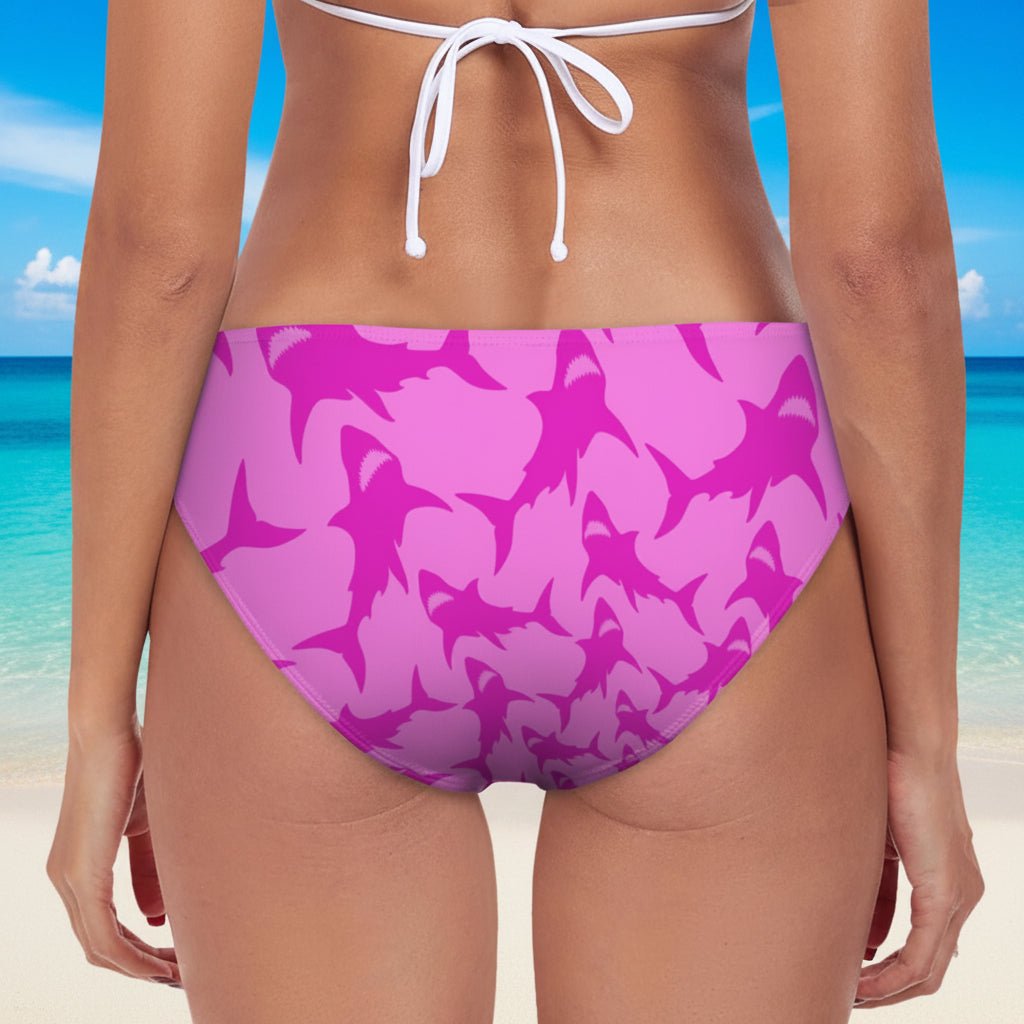 pink shark pattern bikini bottom with white tie-back on a beach background