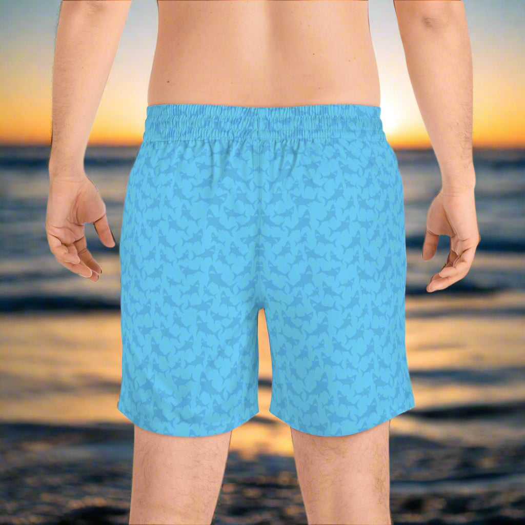 Backside of surfer wearing blue tone shark shorts as he awaits high tide
