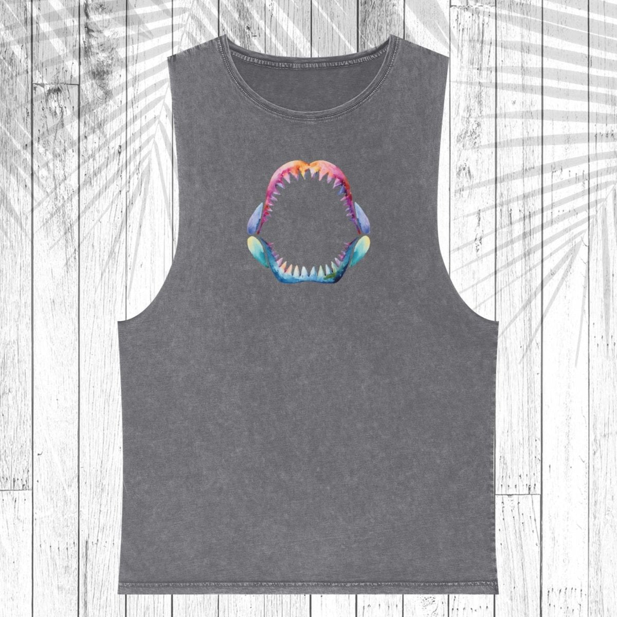 A dark gray sleeveless muscle tank top featuring a colorful graphic of an open shark mouth on the chest, displayed flat against a white wood plank background with a palm leaf overlay.