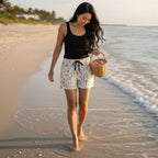 beautiful woman with long black hair walking along the beach looking for seashells on Sanibel Island  in Beach shorts with a sandy color shell pattern 