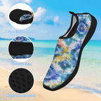 A single water shoe floating over a California beach background, with three circular inset detail callouts showing flexibility, breathable lining, and water-permeable outsole. The shoe has a multicolor tie-dye pattern in blue, purple, yellow, and white with black trim.