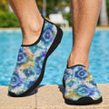A man standing by a swimming pool wearing slip-on water shoes with a blue, purple, and yellow tie-dye pattern and black trim.
