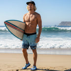 surfer wearing a pair of slip-on water shoes with a vibrant blue, yellow, and white shibori tie-dye pattern, featuring black soles and trim, shown against a plain white background.