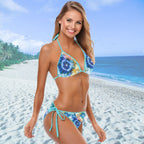 Woman in a colorful Shibori bikini standing on a beach with ocean and sky in the background