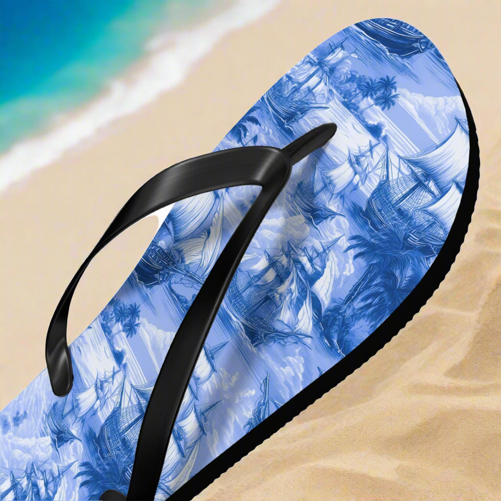 Blue nautical flip-flop sandal with a black strap on a sandy white beach background
