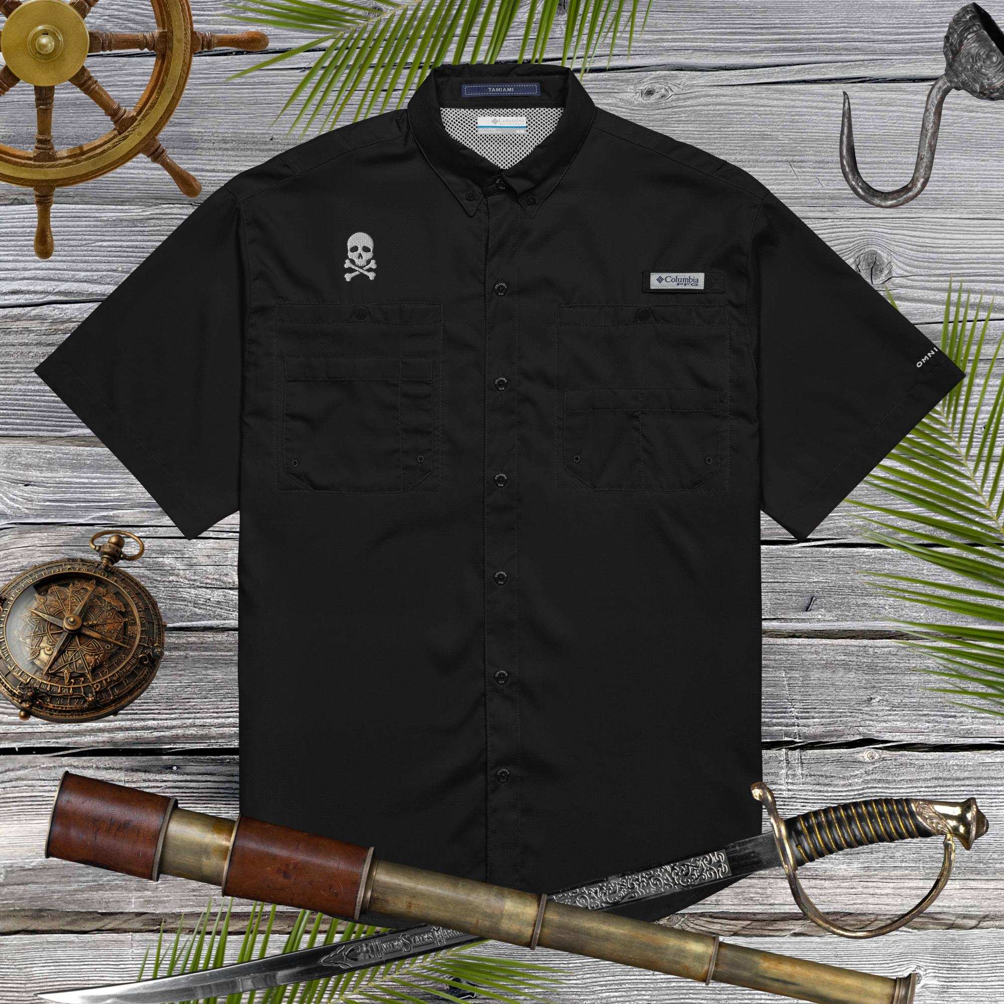 Black short-sleeve shirt with pirate skull embroidery on a wooden surface with nautical-themed props.
