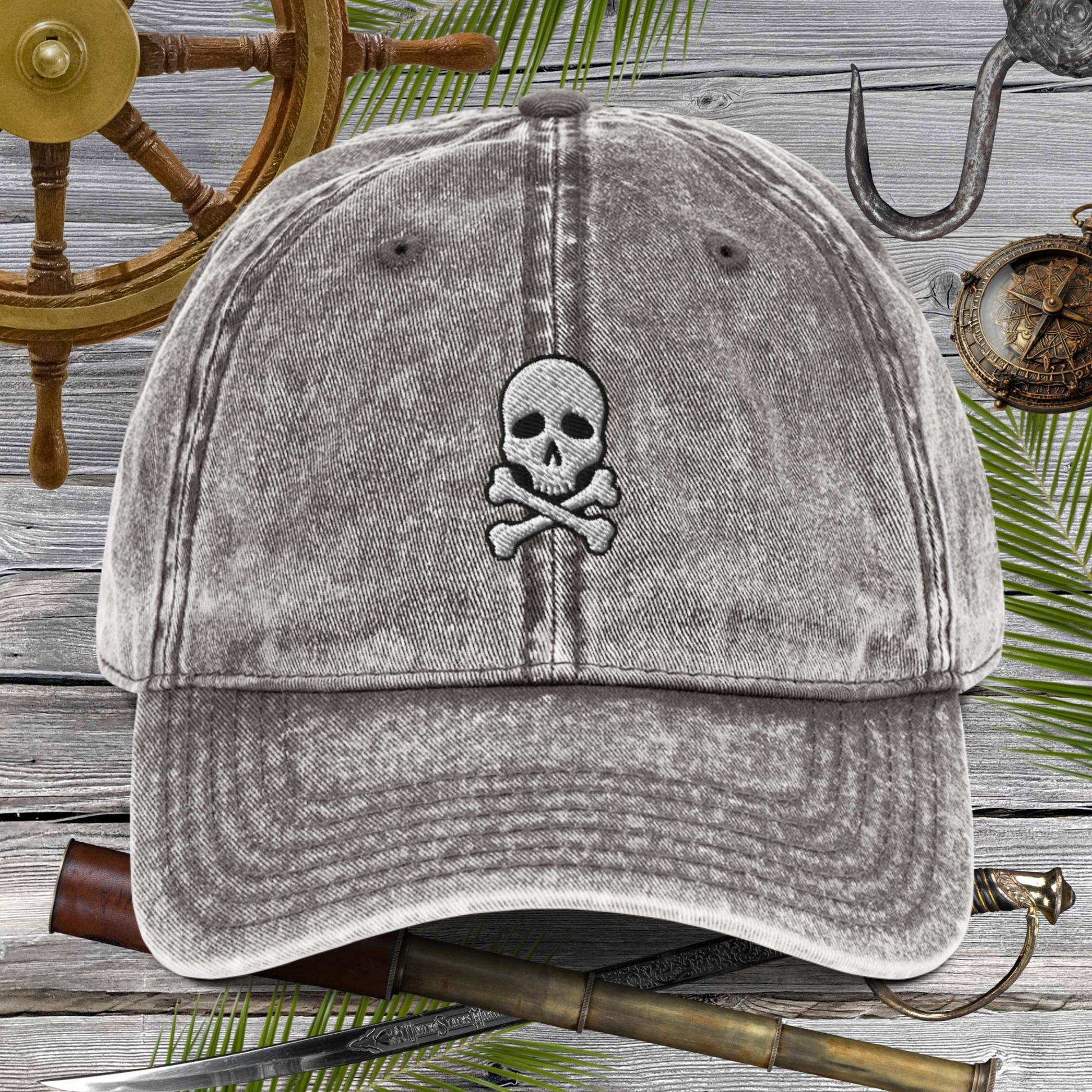 Skull And Crossbones Vintage Cotton Twill Cap featured on a rustic wooden backdrop with nautical decor.