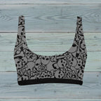 Gray crop swim top with black skull pattern on a rustic wood background