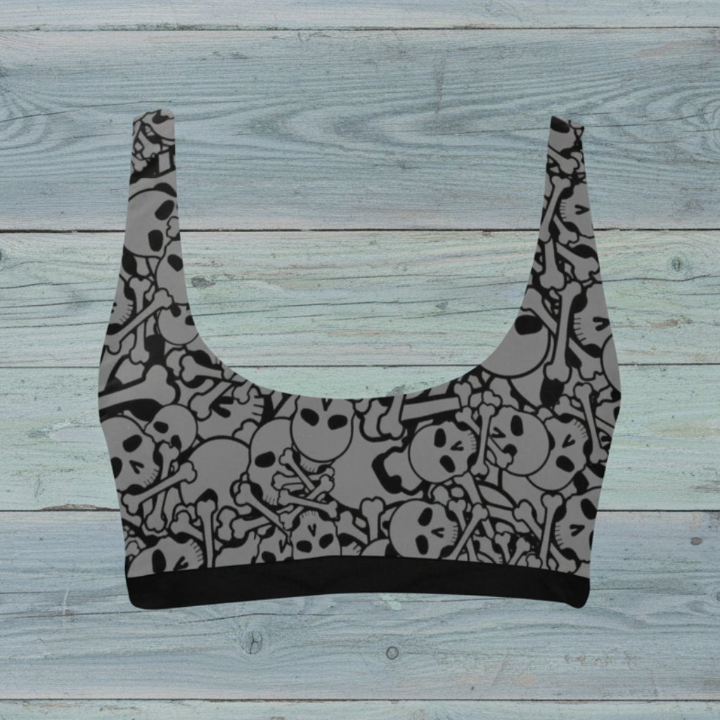 Gray crop swim top with black skull pattern on a rustic wood background