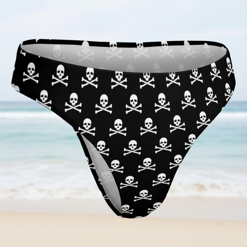 Womens' Black bikini bottoms with white skull and crossbones pattern on a faded beach background