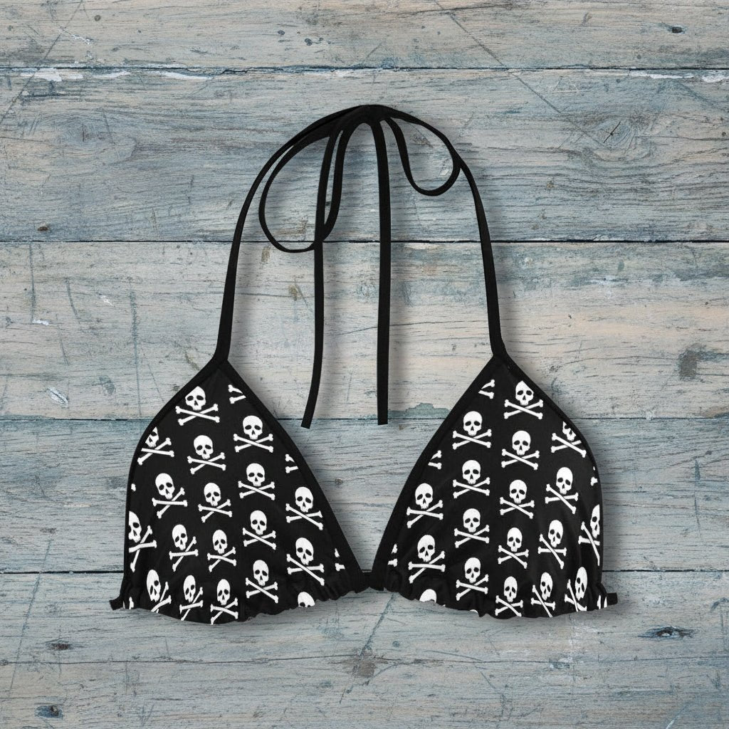 Black bikini top with skull and crossbones pattern on a rustic wood background