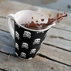 Skull & Crossbones Latte Mug with Edgy Black Design for Coffee Lovers on rustic beachside table with coffee splashing out of the cup