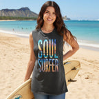 A woman modeling a dark gray acid-wash sleeveless t-shirt with 'SOUL SURFER' printed on the front in a colorful beach scene masked inside the letters paired with blue jeans shorts against a plain white background.