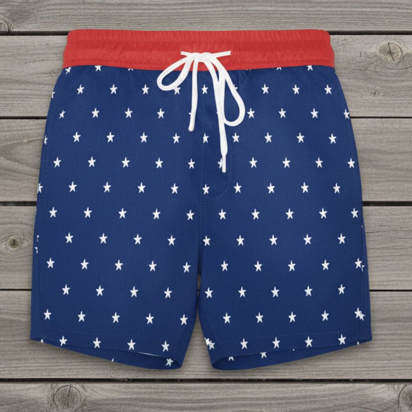 Blue swim shorts with white star pattern and red waistband on a rustic nautical wood background