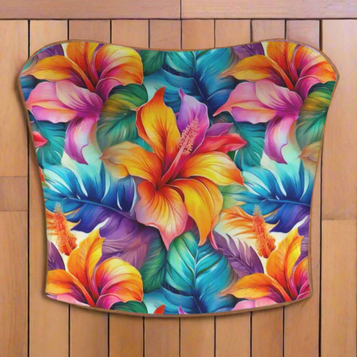 Colorful strapless top with tropical floral design laying flat on the deck of a vintage sailboat. 
