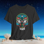 A dark charcoal gray t-shirt featuring a colorful Mexican sugar skull graphic, displayed against a beach and starry night sky background.