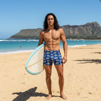 Man holding a surfboard on a Hawaiian beach with Diamond Head Mountain in the background