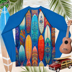 Blue rash guard with colorful surfboard design, surrounded by surfboards, a guitar, and a model woody car.