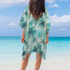 Person wearing a palm tree patterned cover-up by the beach