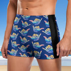 Blue swim shorts with colorful shaka hand signs pattern on a beach background