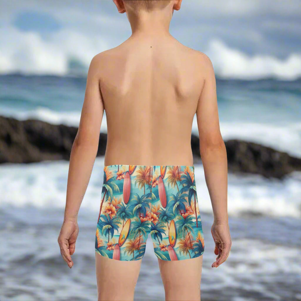 Child wearing colorful tropical-surf-themed swim trunks, looking out over the Pacific Ocean on the Hawaiian North Shore